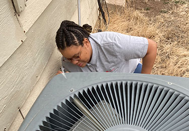 Zaniiya Olagoke — professional home inspector — inspecting an airconditioning unit.